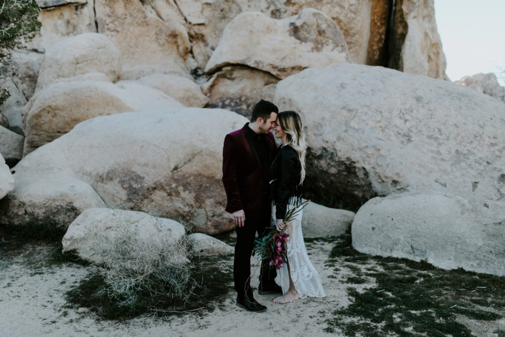 Alyssa and Jeremy look lovingly at each other near the rocks in Joshua Tree National Park.