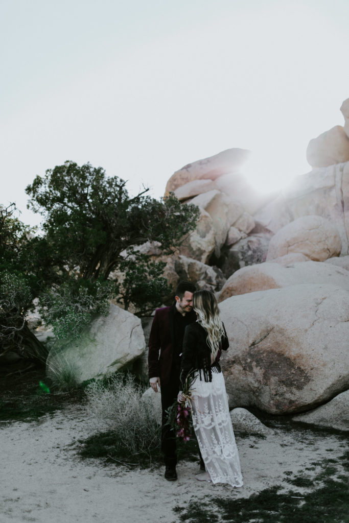 Alyssa and Jeremy stand in front of the setting sun in Joshua Tree National Park.