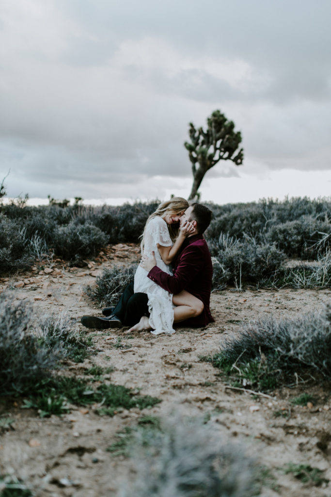 Alyssa and Jeremy kiss in the sand of Joshua Tree National Park.