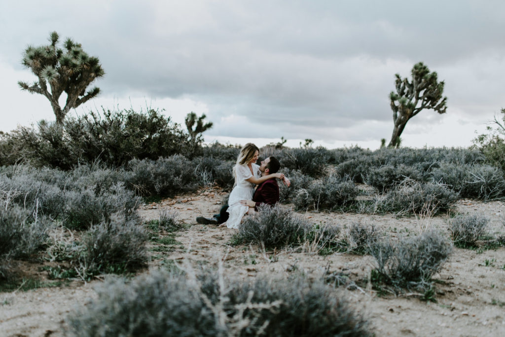 Jeremy and Alyssa sit in the sand in Joshua Tree National Park.